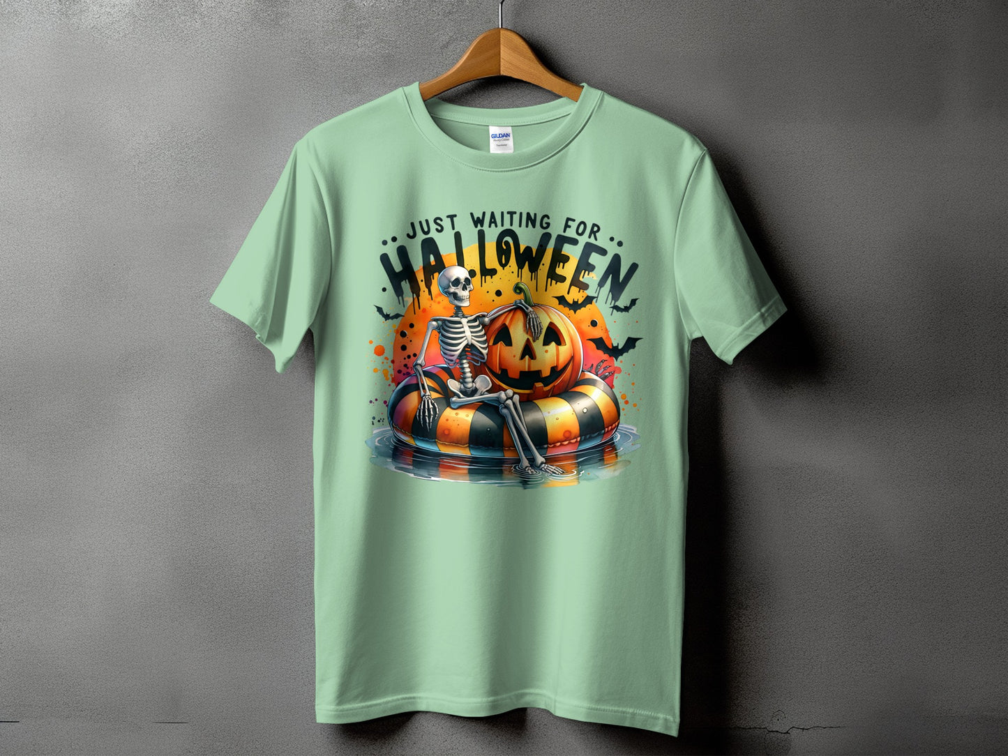 Light green t-shirt with a skeleton on a Halloween float and the text "Just Waiting For Halloween."