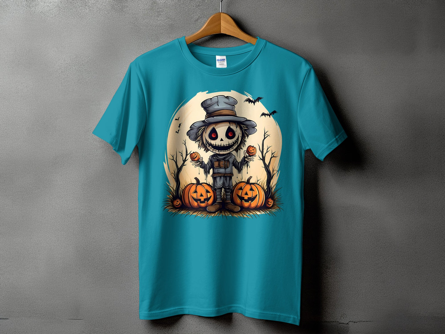 Teal t-shirt with Halloween scarecrow graphic holding pumpkins and bats.