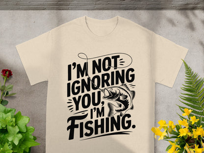 Cream t-shirt with black text and fish graphic saying "I'm Not Ignoring You, I'm Fishing."