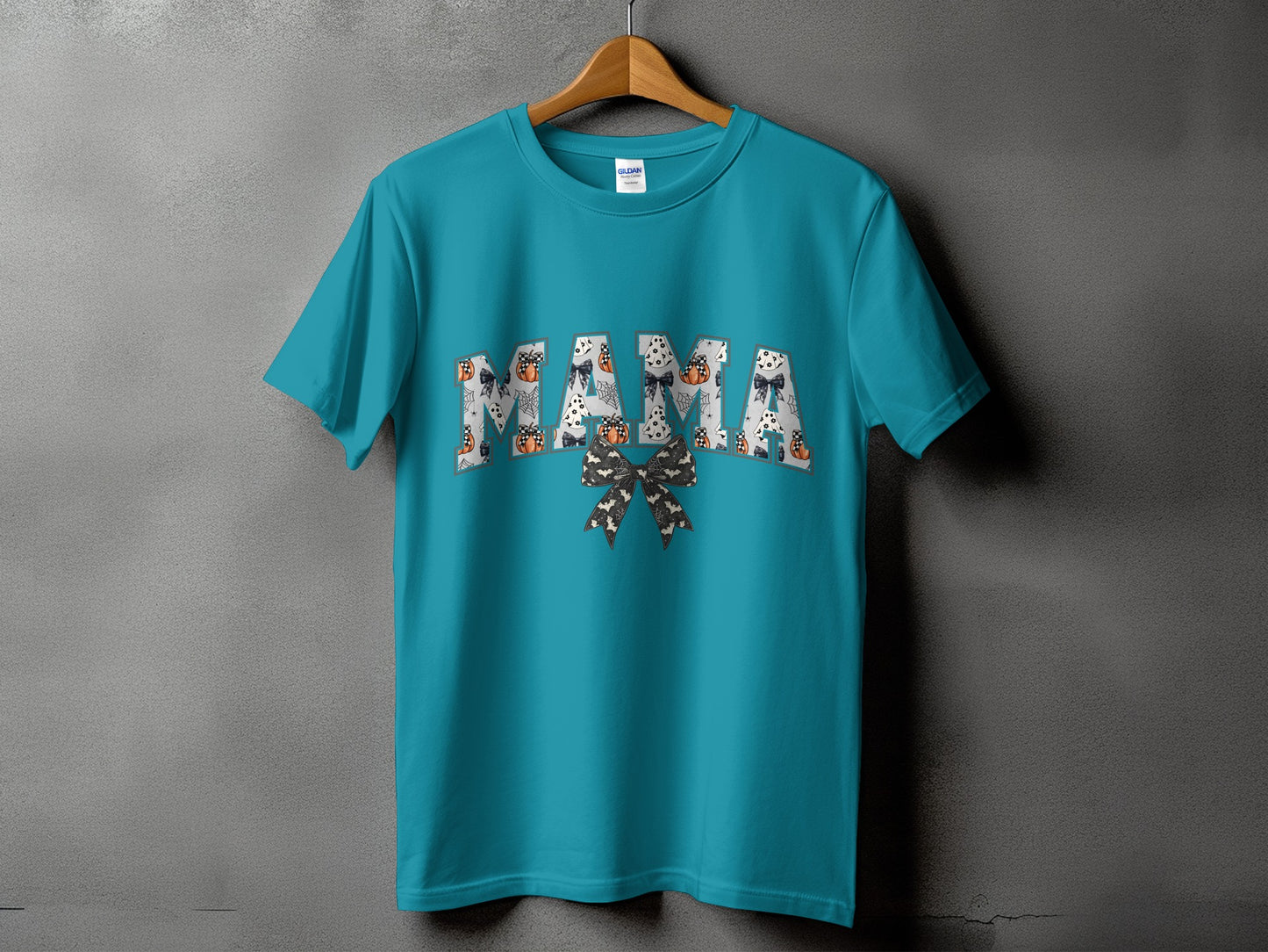 Teal t-shirt with "MAMA" text filled with Halloween patterns and a bow.