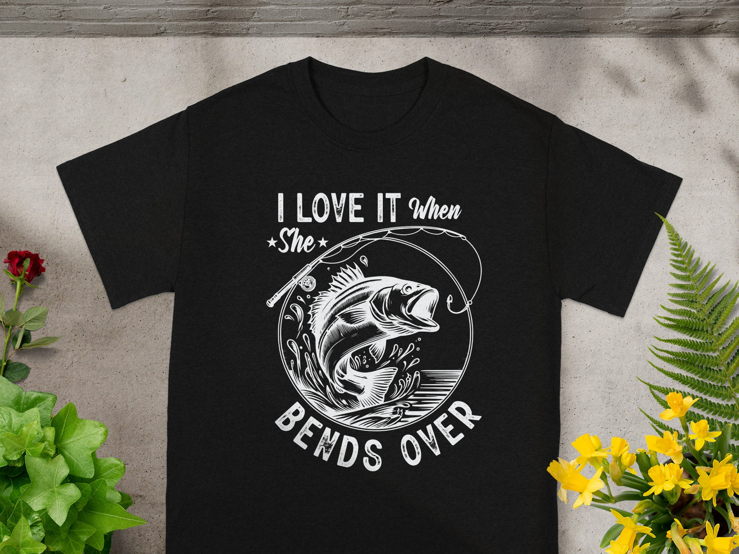 Black t-shirt with white graphic "I Love It When She Bends Over" and a fish jumping from water.