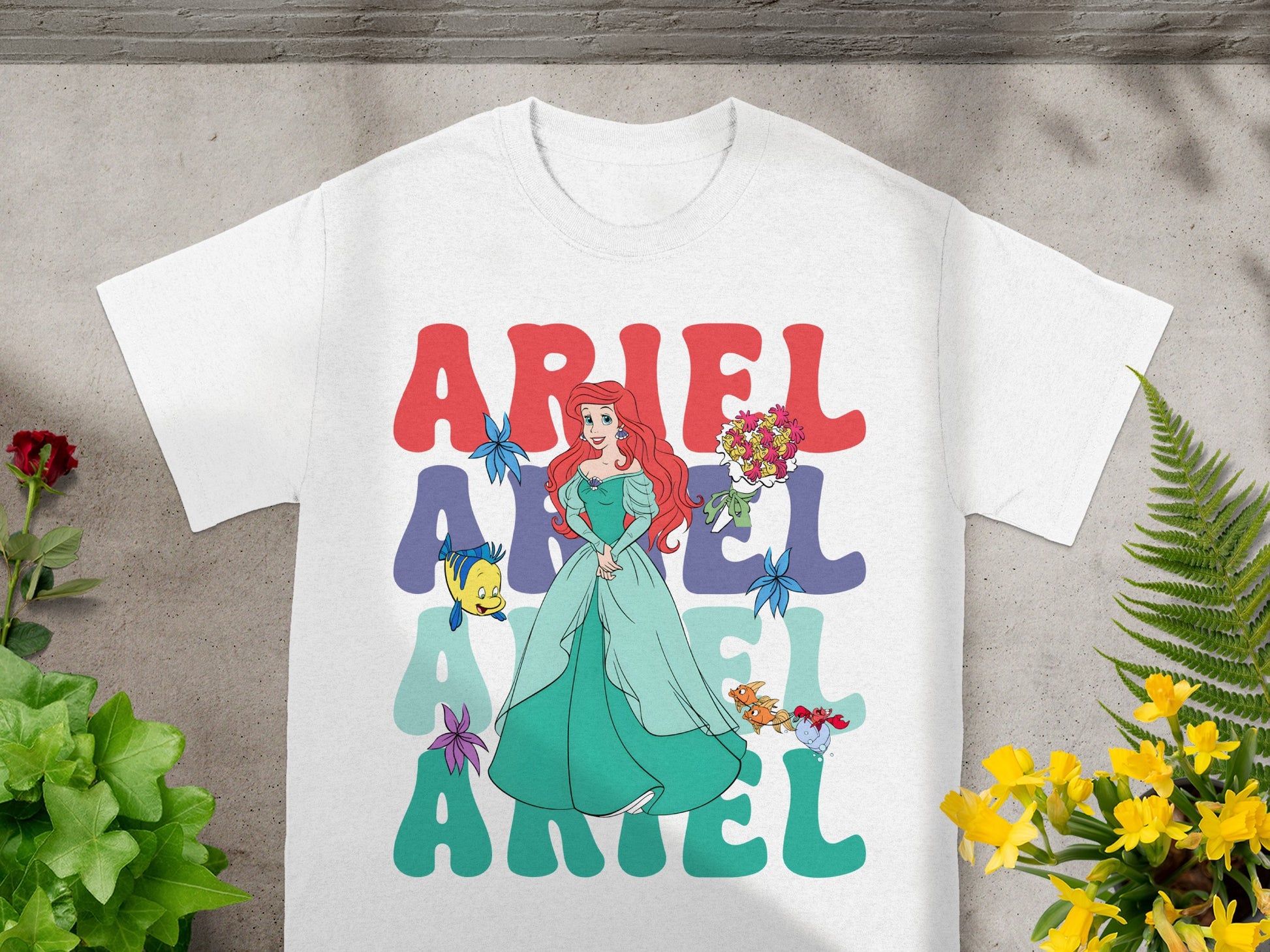 White t-shirt with Ariel from The Little Mermaid illustration and text.