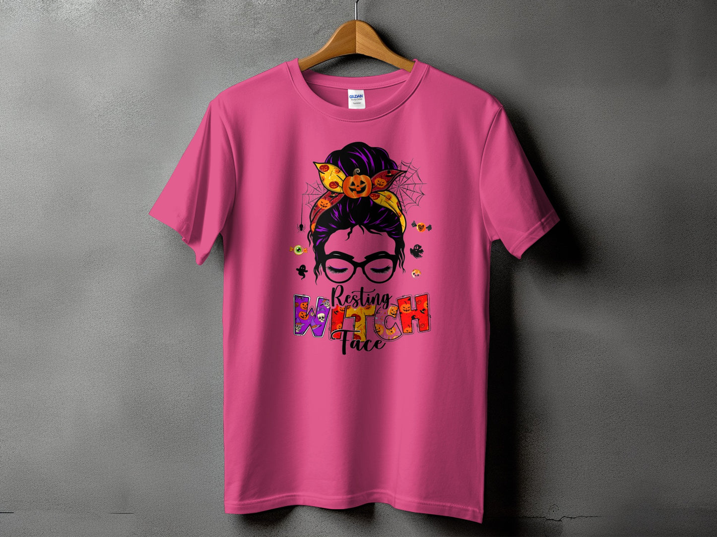 Pink t-shirt with Halloween graphic featuring a messy bun, pumpkin, and "Resting Witch Face" text.