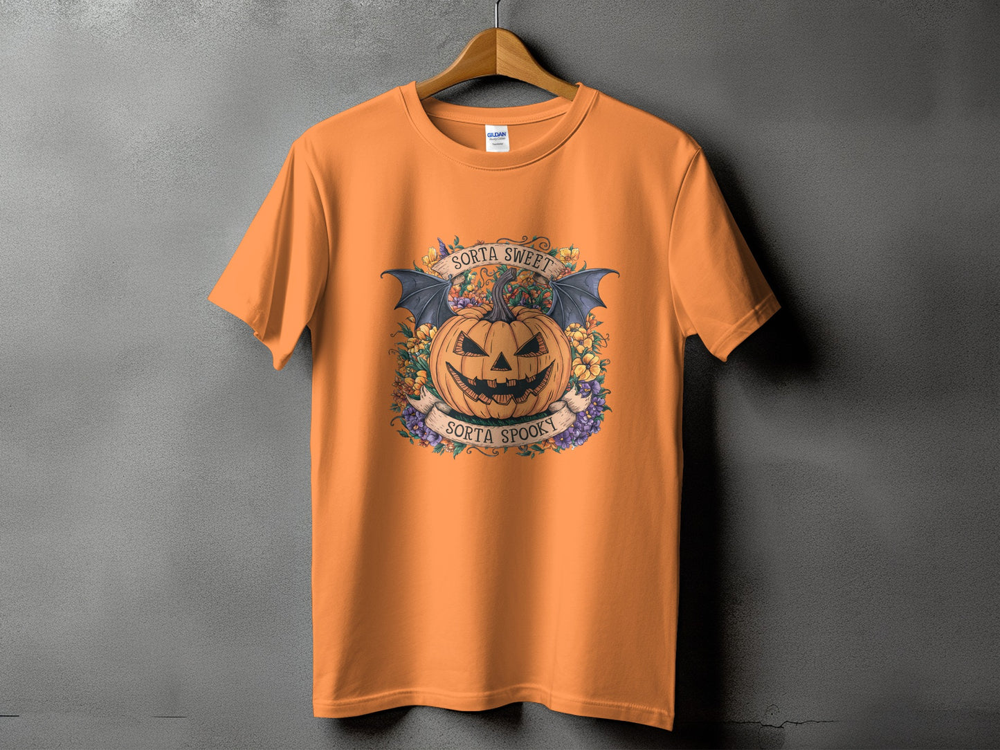Orange t-shirt with a Halloween design featuring a pumpkin, bats, and text.
