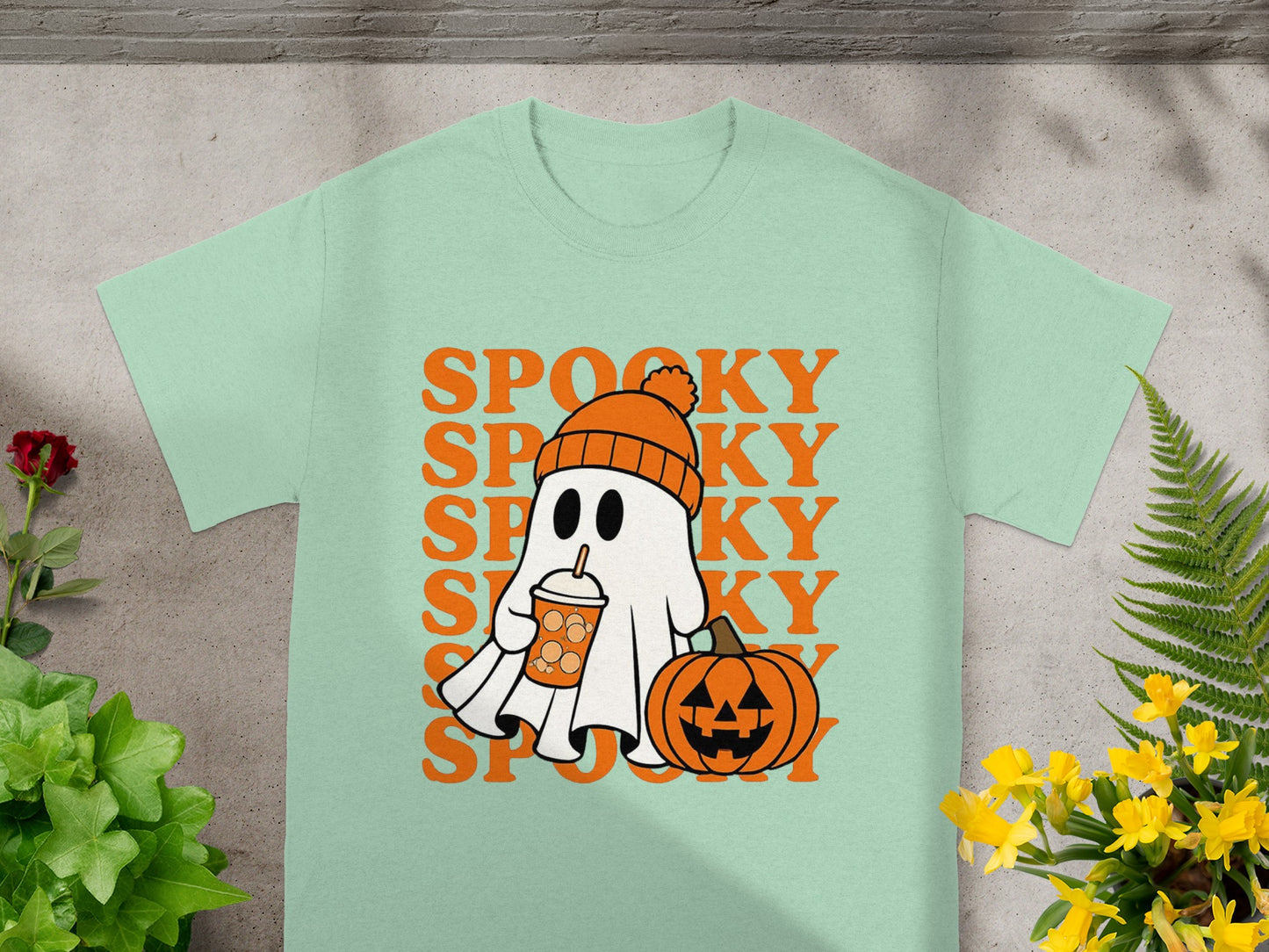 Ghost with drink and pumpkin on mint t-shirt with repeating "Spooky" text.