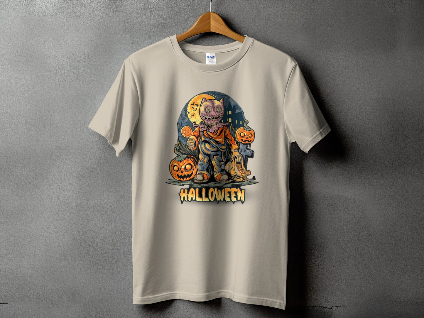 Light tan t-shirt with a Halloween-themed graphic of a scarecrow holding a lollipop and pumpkins.