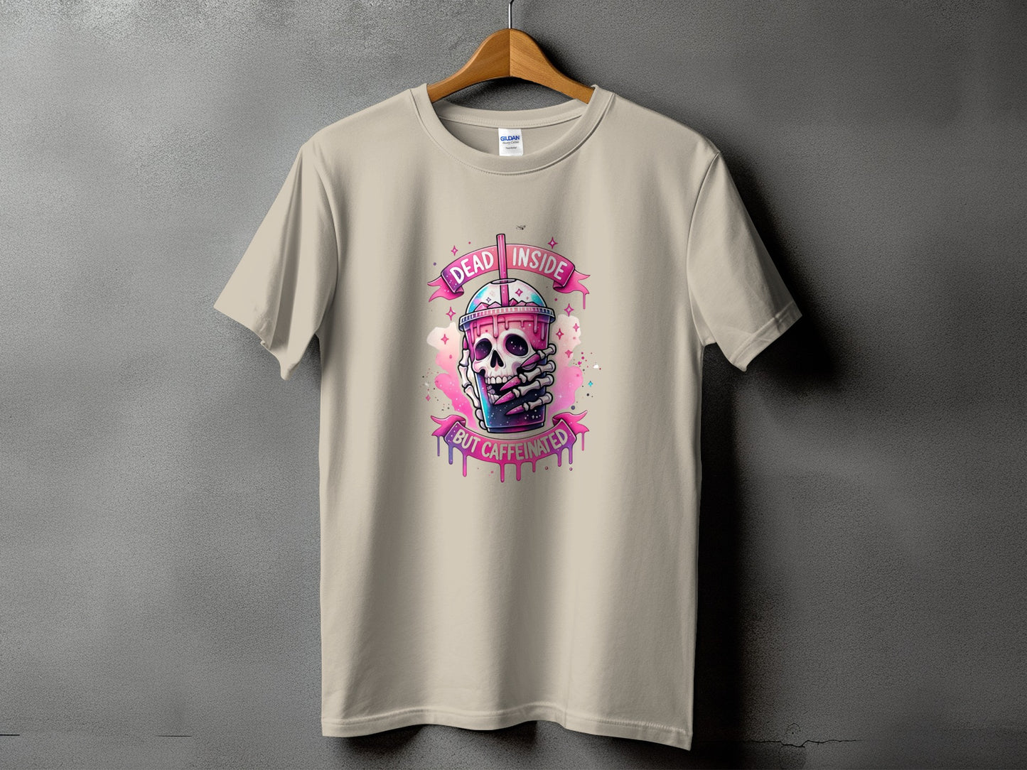 Beige t-shirt with skull holding iced coffee graphic and text "DEAD INSIDE BUT CAFFEINATED".