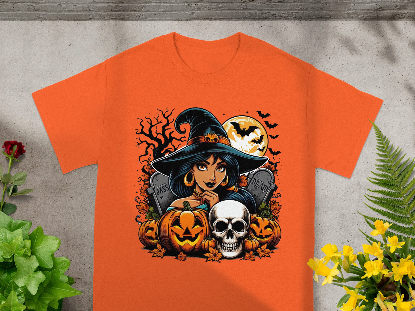 Halloween graphic on orange t-shirt with witch, pumpkins, skull, and gravestones.