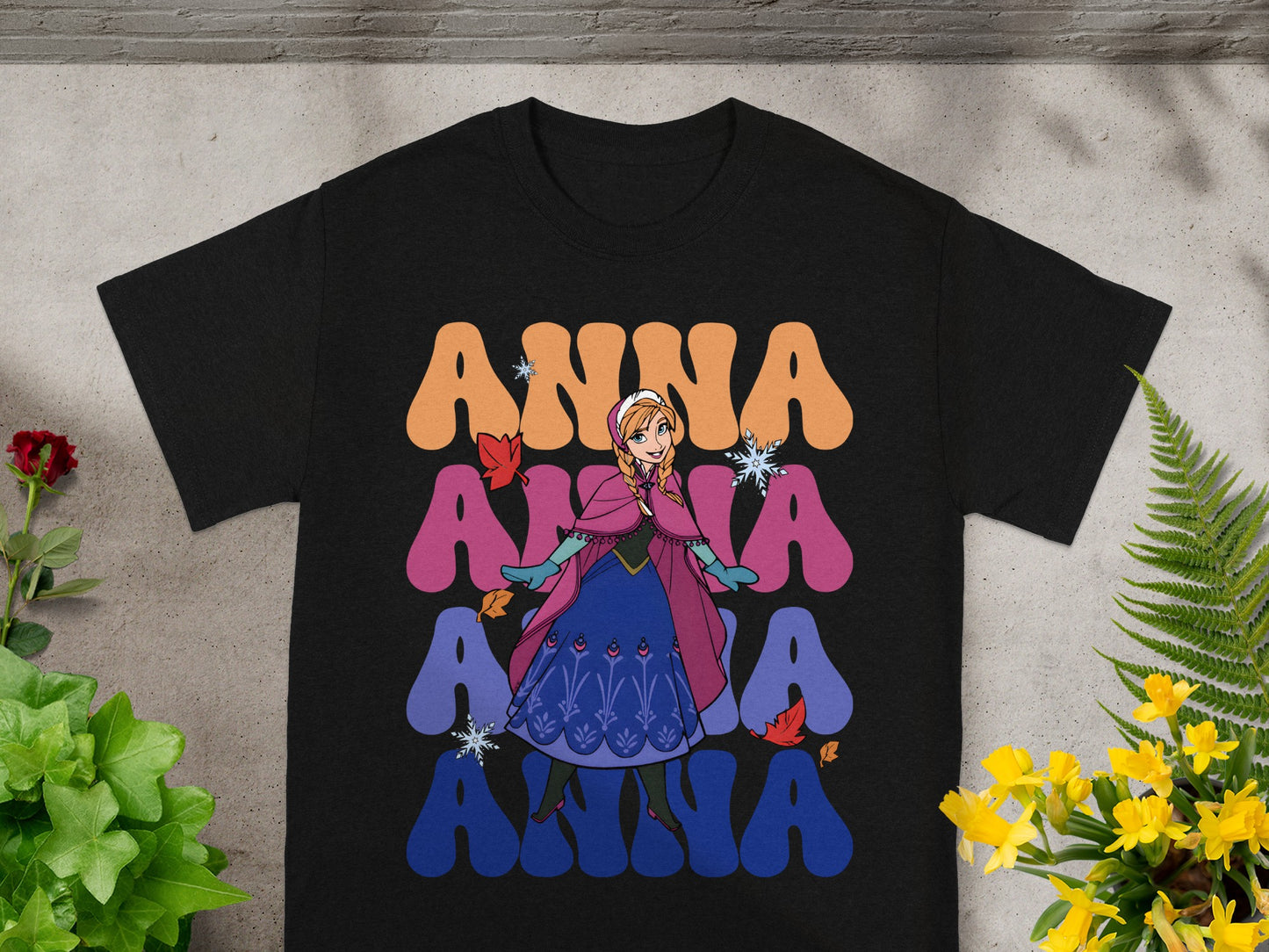 Black t-shirt with Anna from Frozen repeated in colorful lettering.