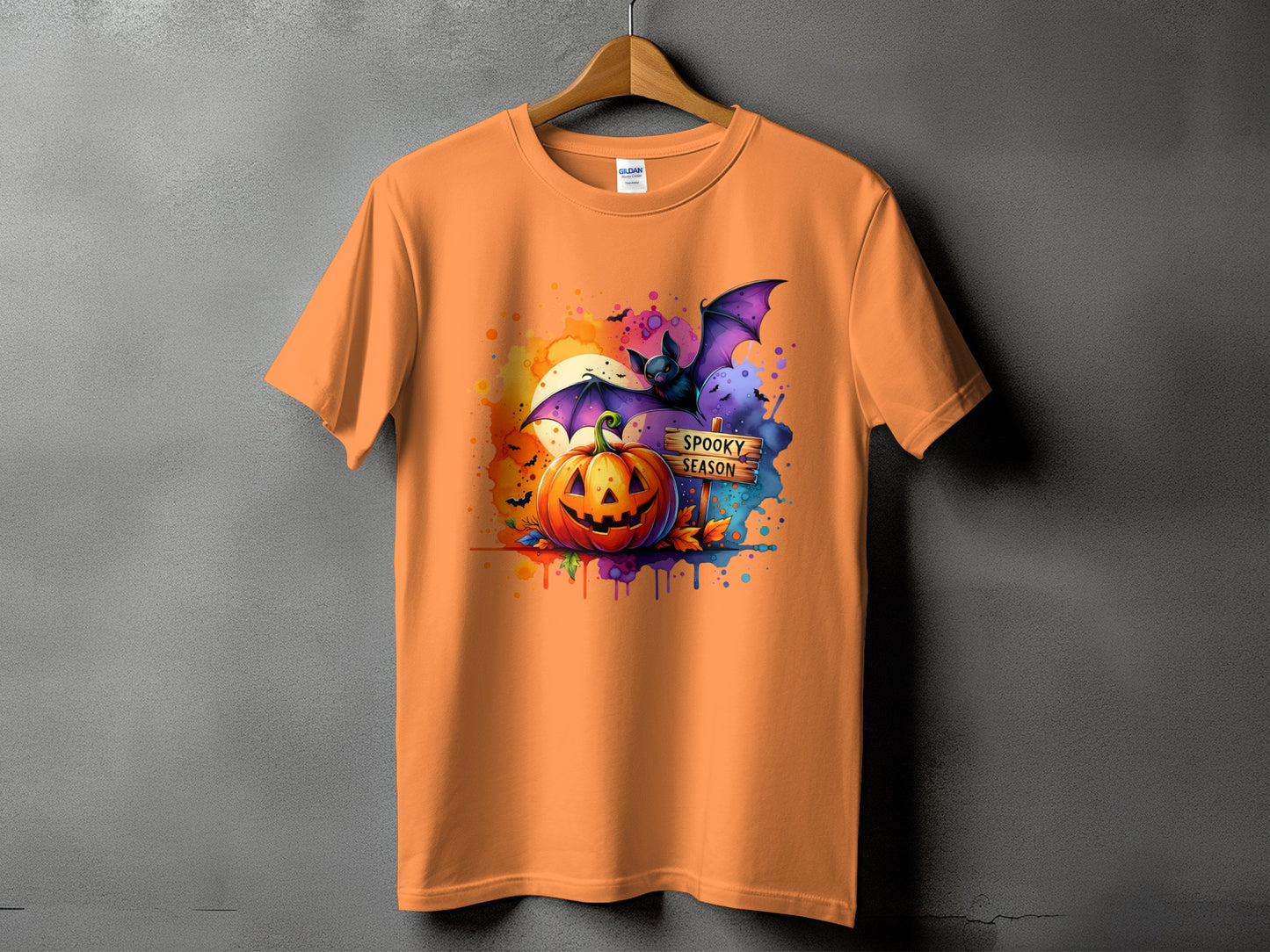 Orange t-shirt with Halloween graphic featuring pumpkin, bat, and "Spooky Season" sign.