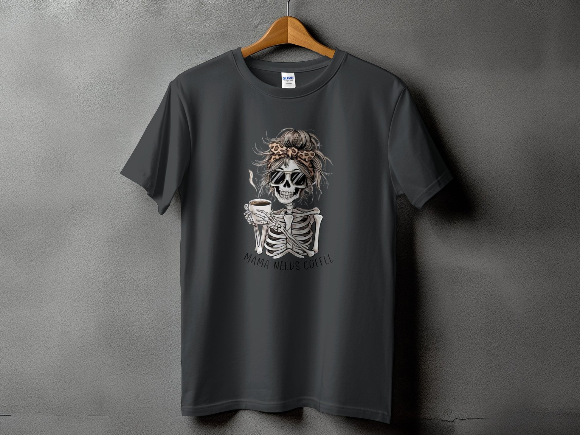Dark grey t-shirt with skeleton holding coffee, text "MAMA NEEDS COFFEE".