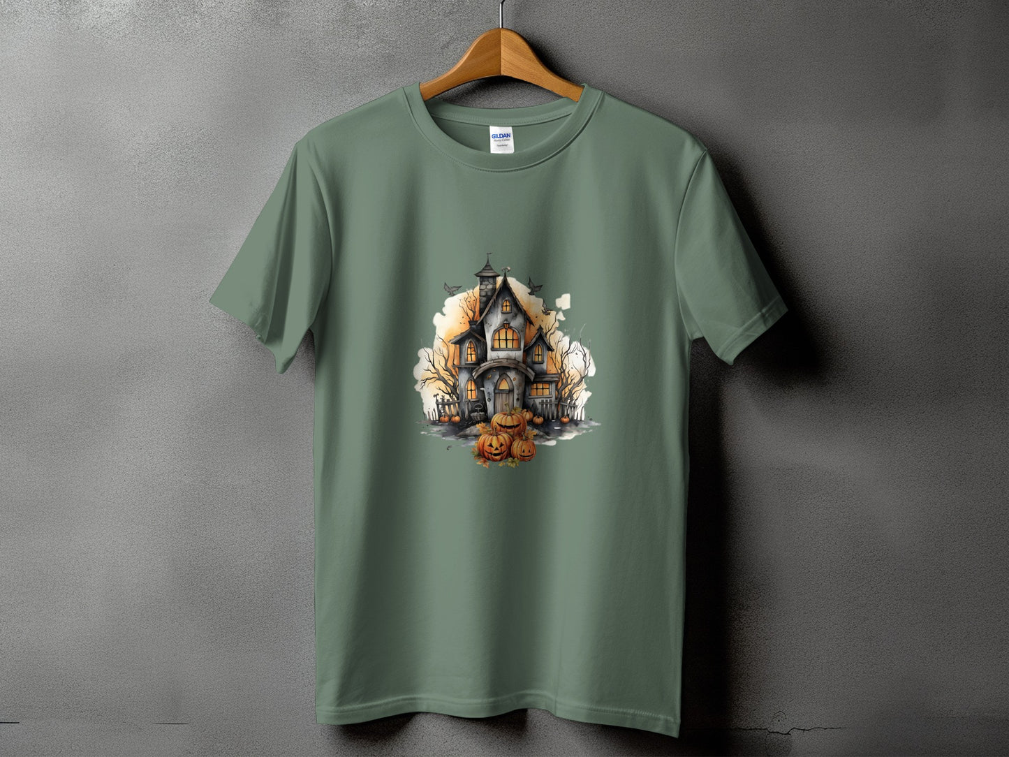 Green t-shirt with a watercolor illustration of a haunted house and pumpkins.