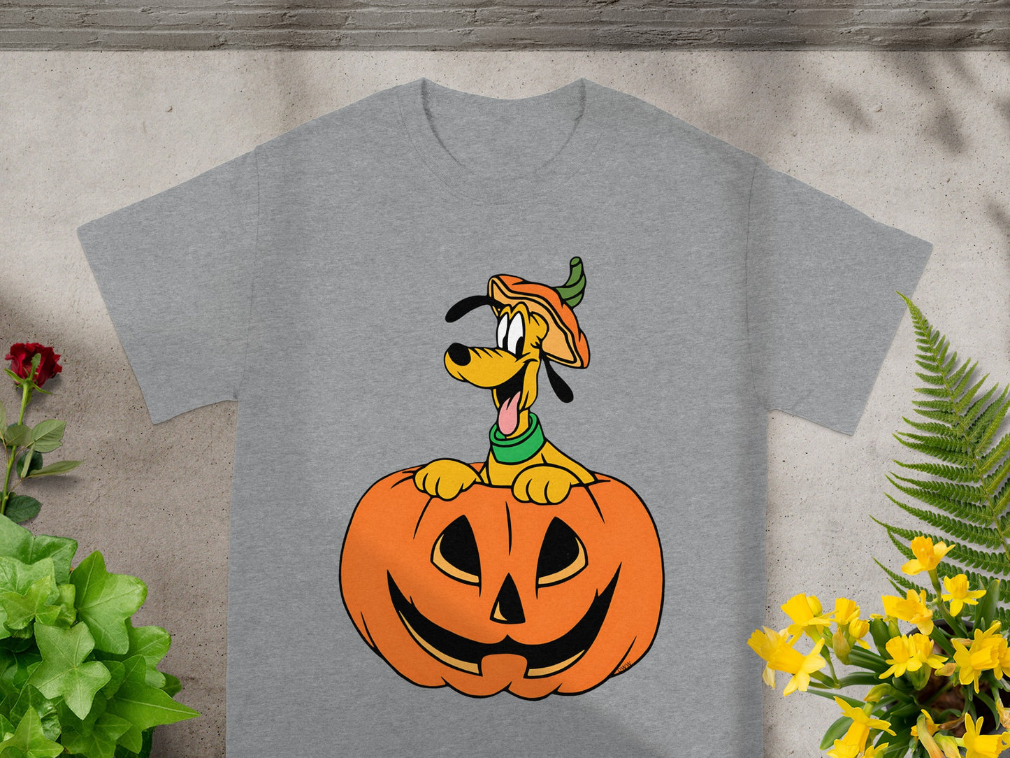 Pluto dog wearing pumpkin hat peeking out of jack-o'-lantern on grey t-shirt.