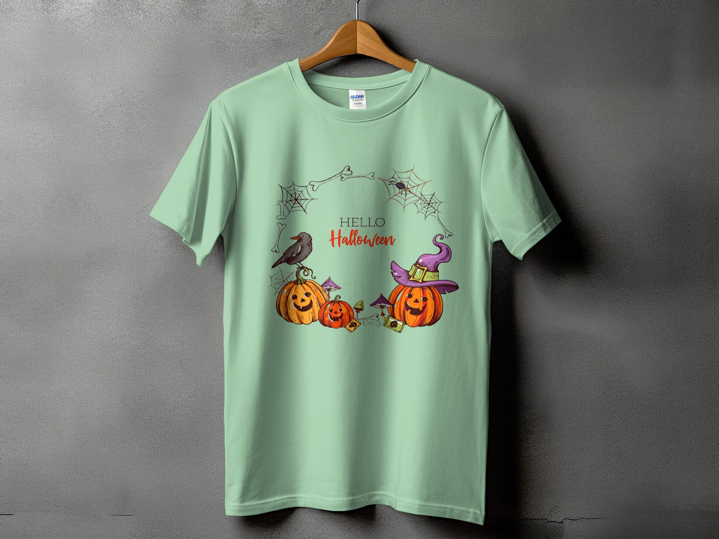 Light green t-shirt with Halloween design featuring pumpkins, a crow, and spiders.