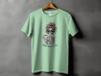 Light green t-shirt with skeleton graphic holding coffee and text "Mama Needs Coffee".