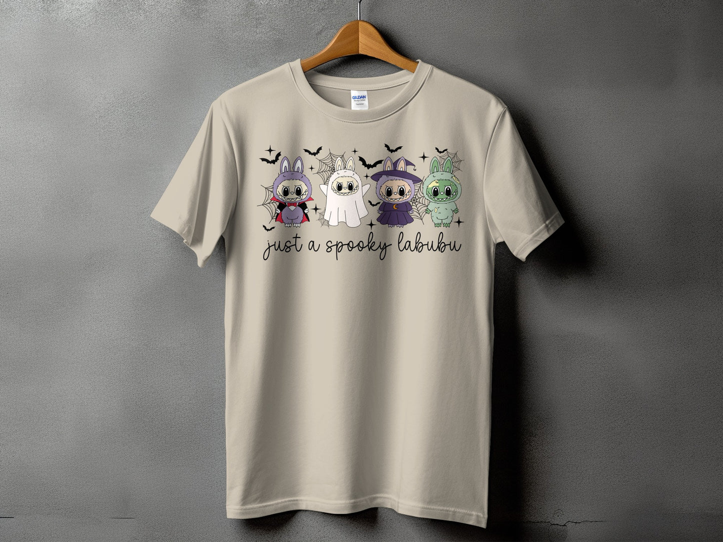 Light tan t-shirt with four Halloween-themed cartoon characters and "just a spooky labubu" text.