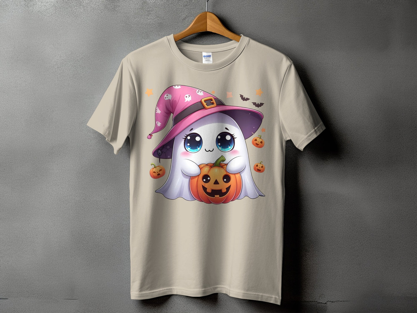 Cute ghost wearing a pink witch hat holds a jack-o'-lantern on a beige t-shirt.