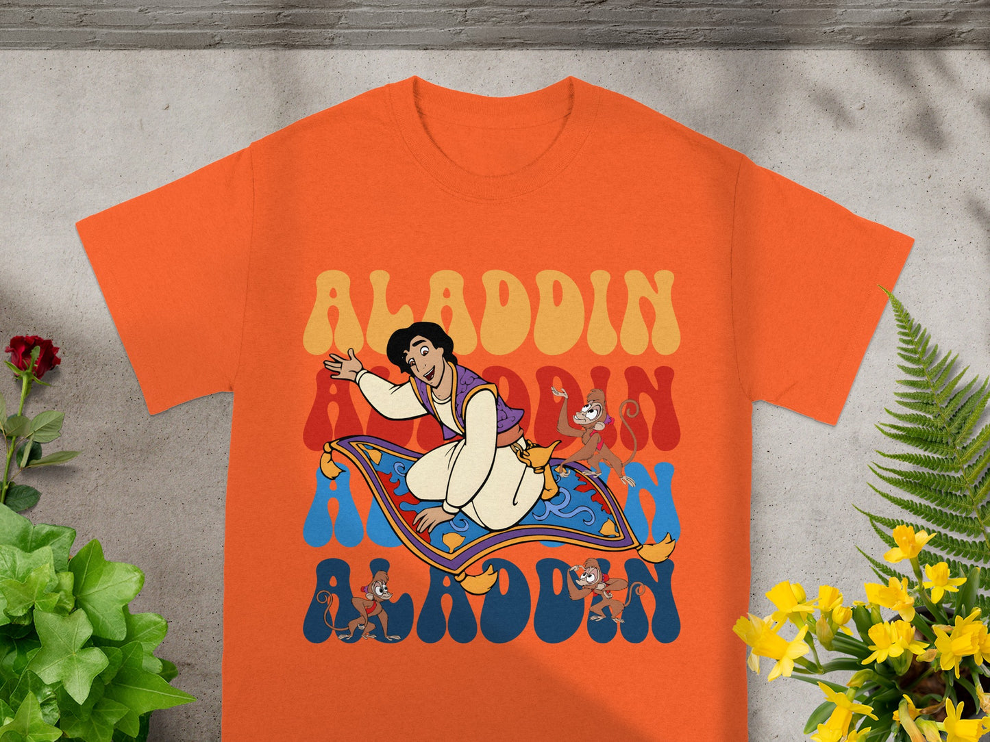 Aladdin and Abu on magic carpet with retro "Aladdin" text.