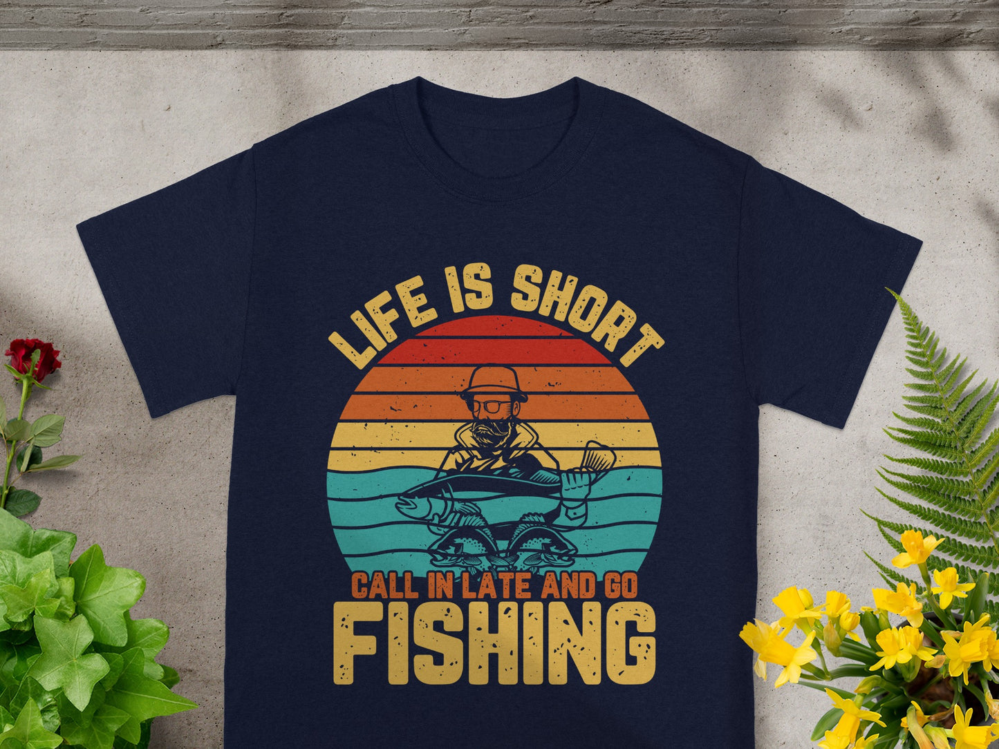 T-shirt with a graphic of a fisherman holding a fish and the text "Life is short, call in late and go fishing".