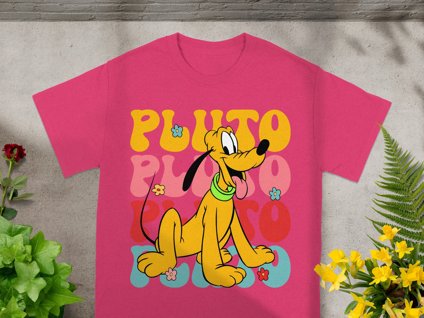 Pink t-shirt with Pluto illustration and "PLUTO" text in colorful retro lettering.