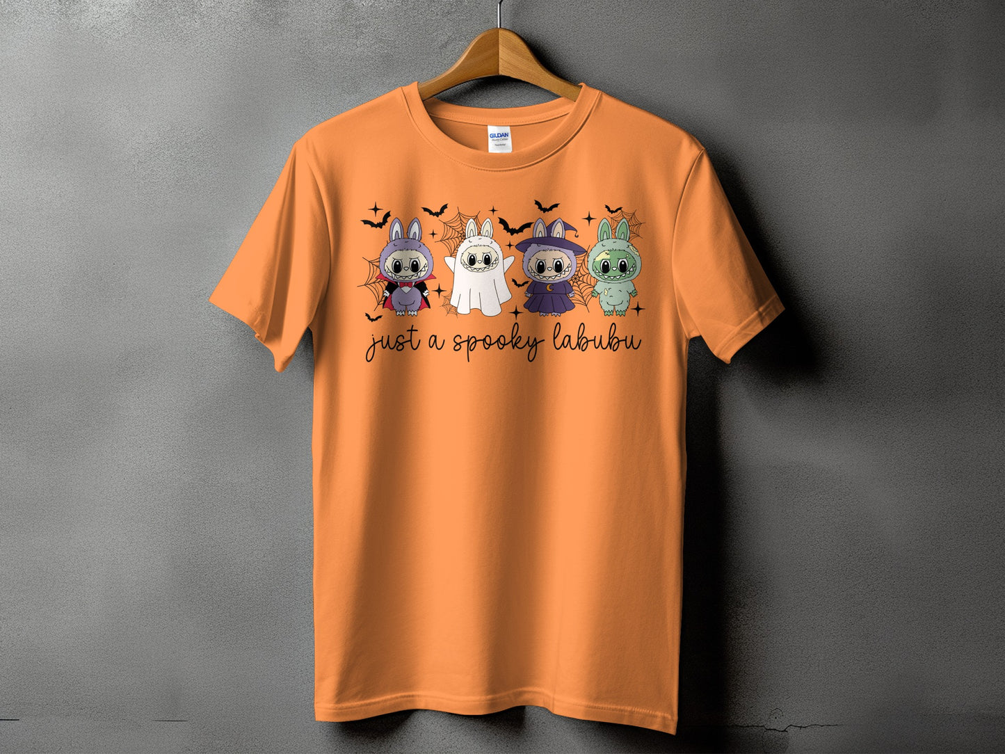Orange t-shirt with four Halloween-themed cartoon bunnies and text "just a spooky labubu".