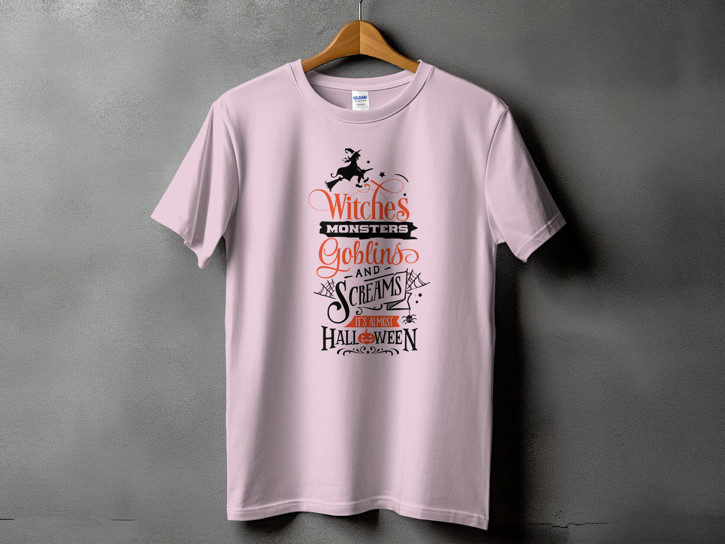 Light pink t-shirt with Halloween graphic: "Witches, Monsters, Goblins and Screams It's Almost Halloween".