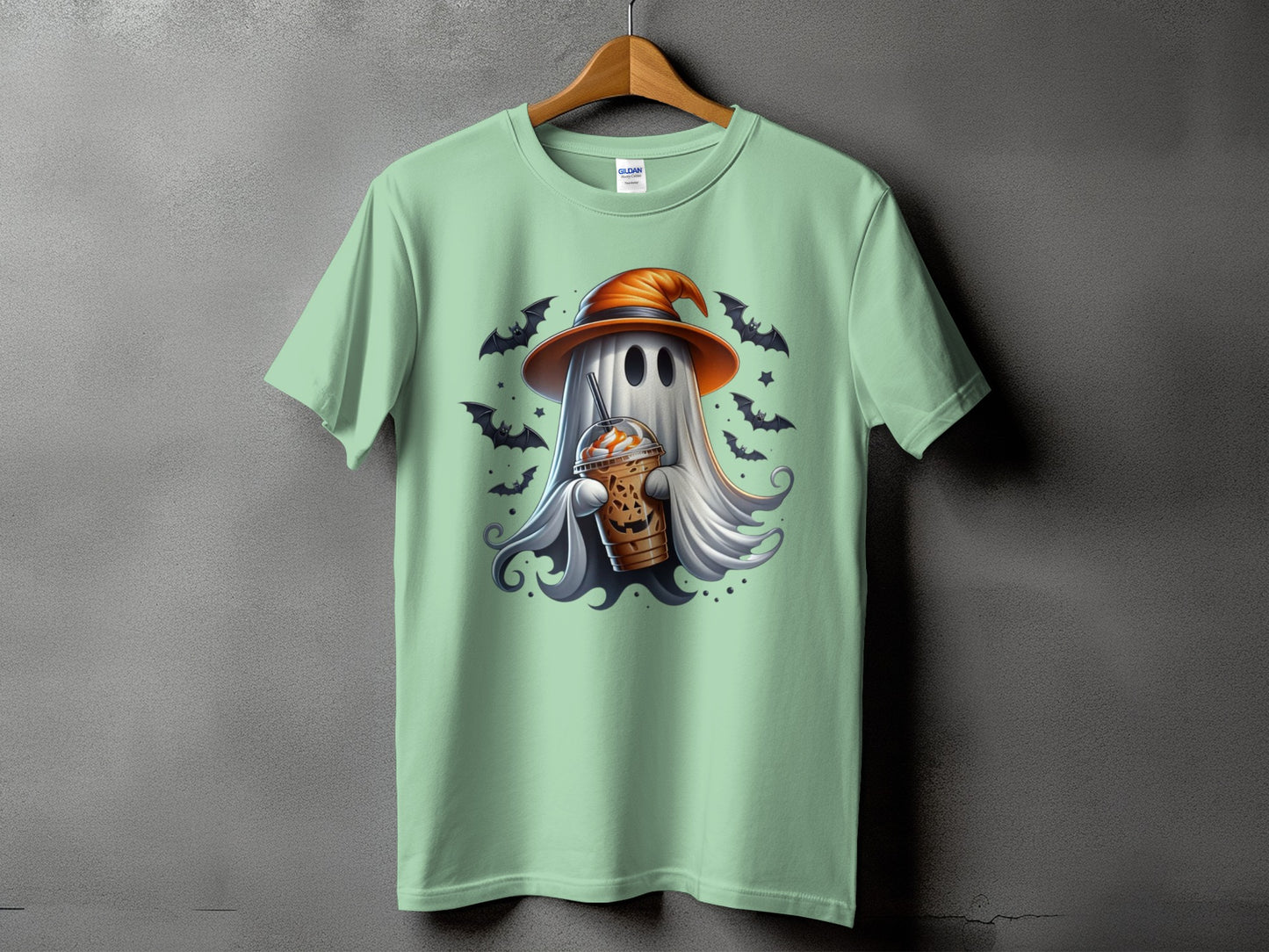 Ghost wearing witch hat holding coffee with bats and stars on a light green t-shirt.