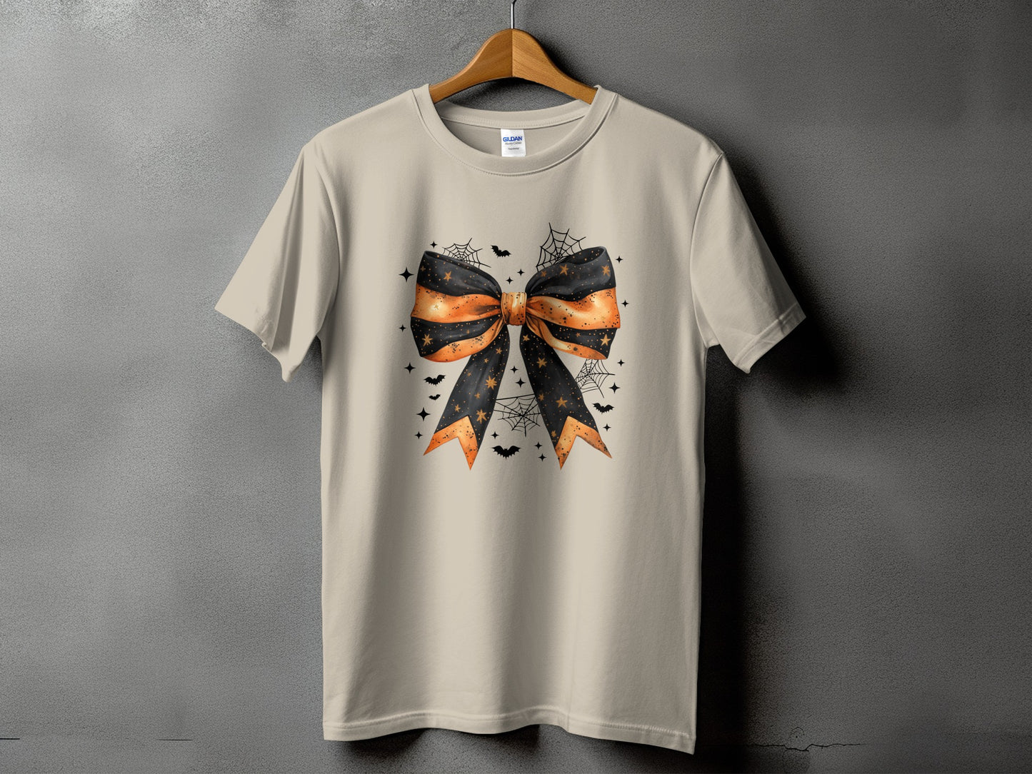 Light tan t-shirt with a Halloween bow graphic, bats, and spiderwebs.