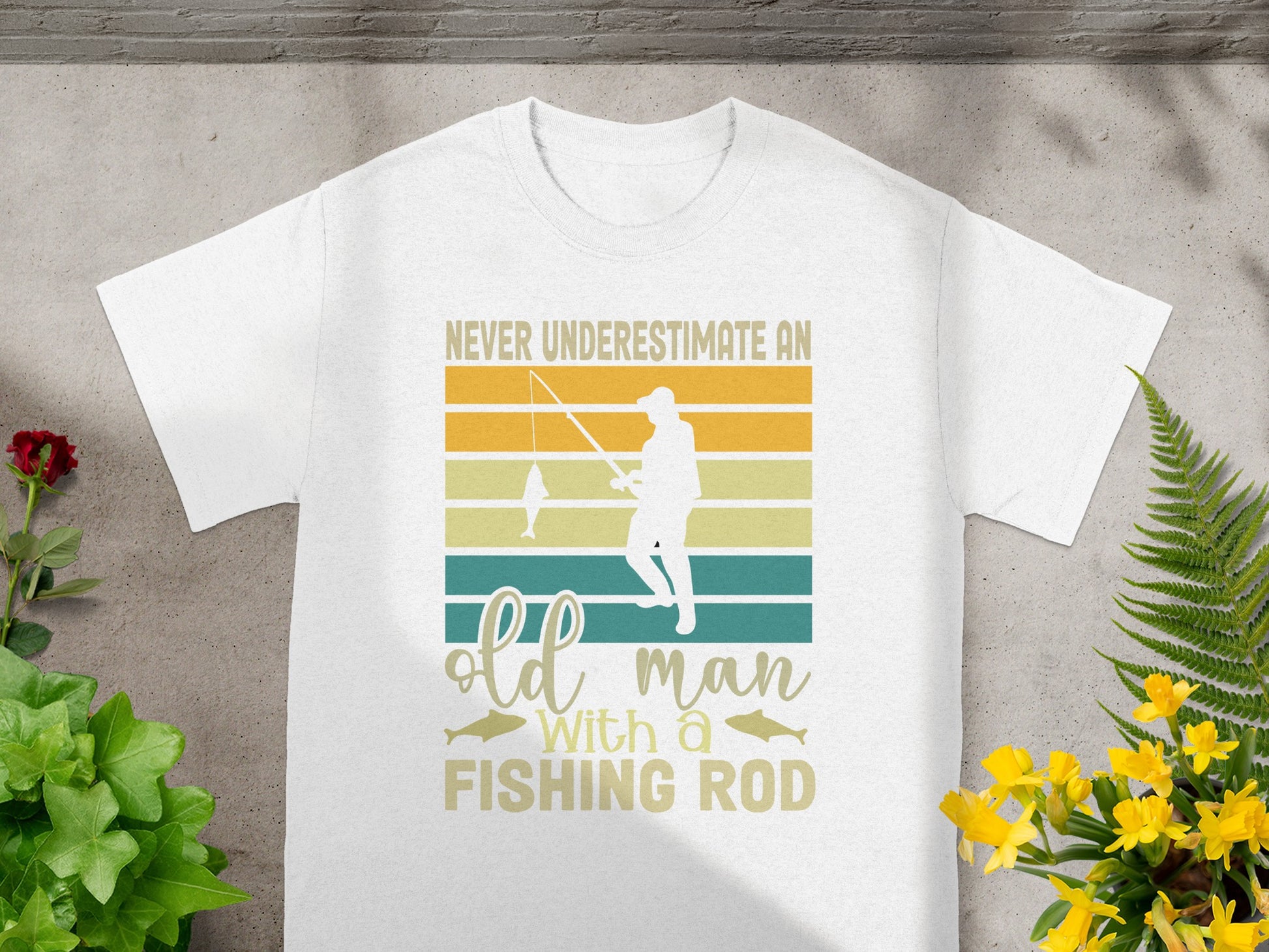 White t-shirt with graphic text "Never Underestimate an Old Man With a Fishing Rod".