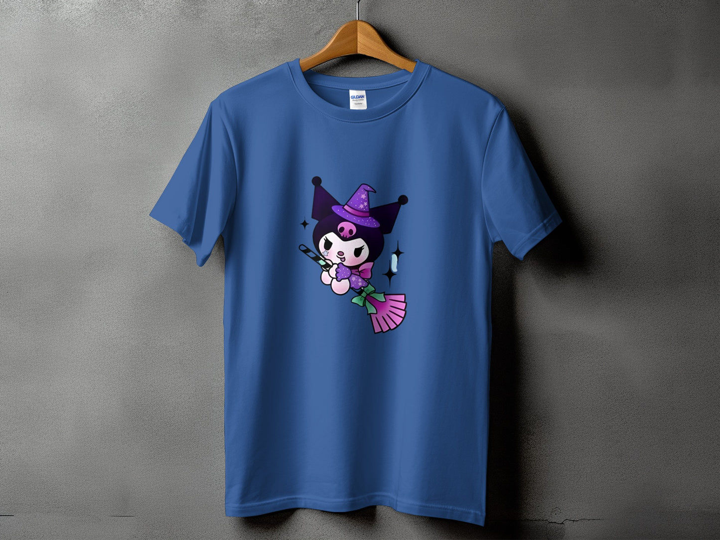 Blue t-shirt with a cartoon character wearing a witch hat and flying on a broom.