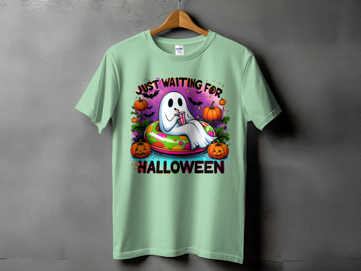 Ghost floating in an inner tube surrounded by pumpkins with text "Just Waiting For Halloween".
