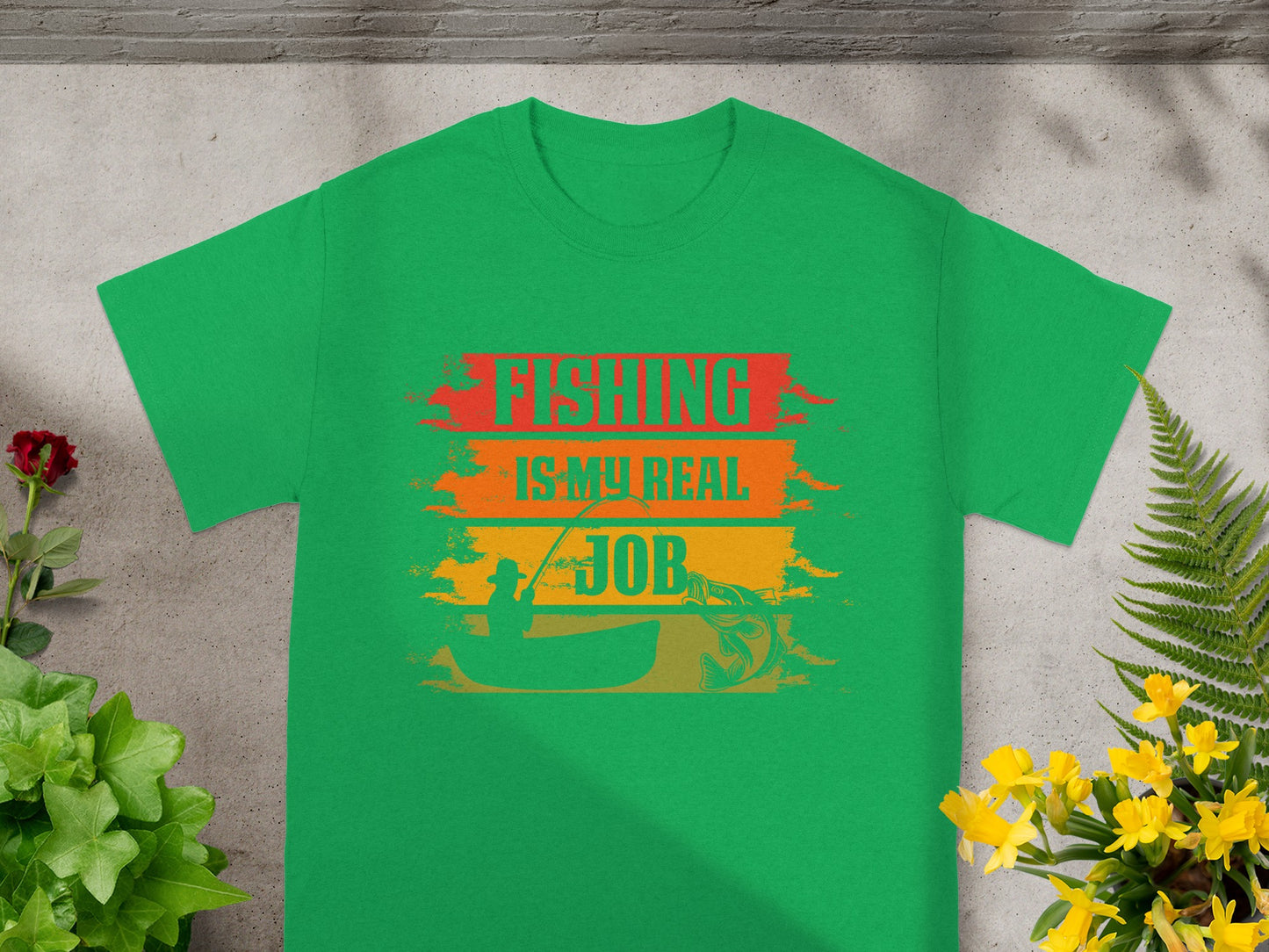 Green t-shirt with text "FISHING IS MY REAL JOB," fisherman, and fish graphic.