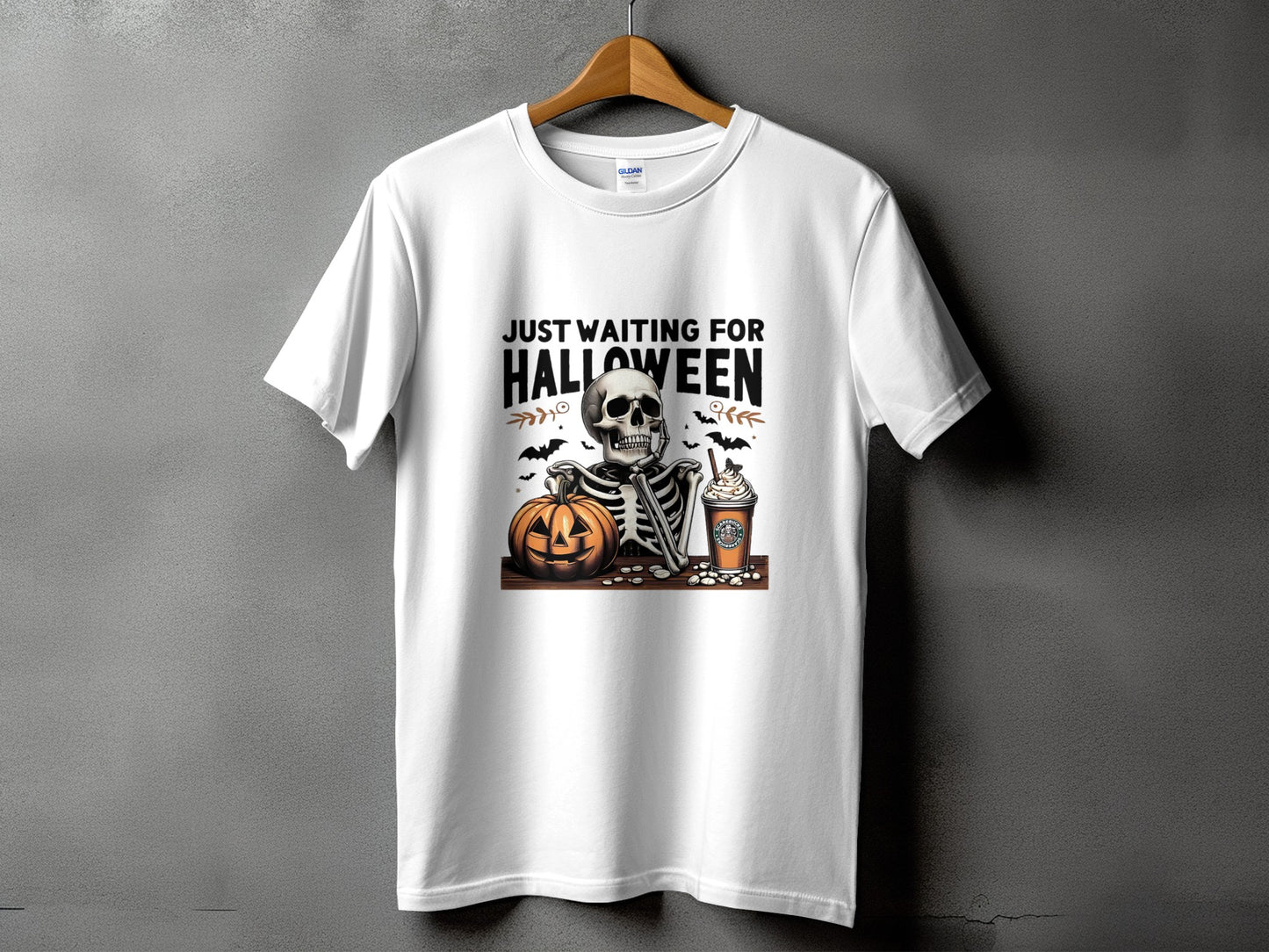 White t-shirt with skeleton, pumpkin, and coffee graphic, reads "Just Waiting For Halloween".