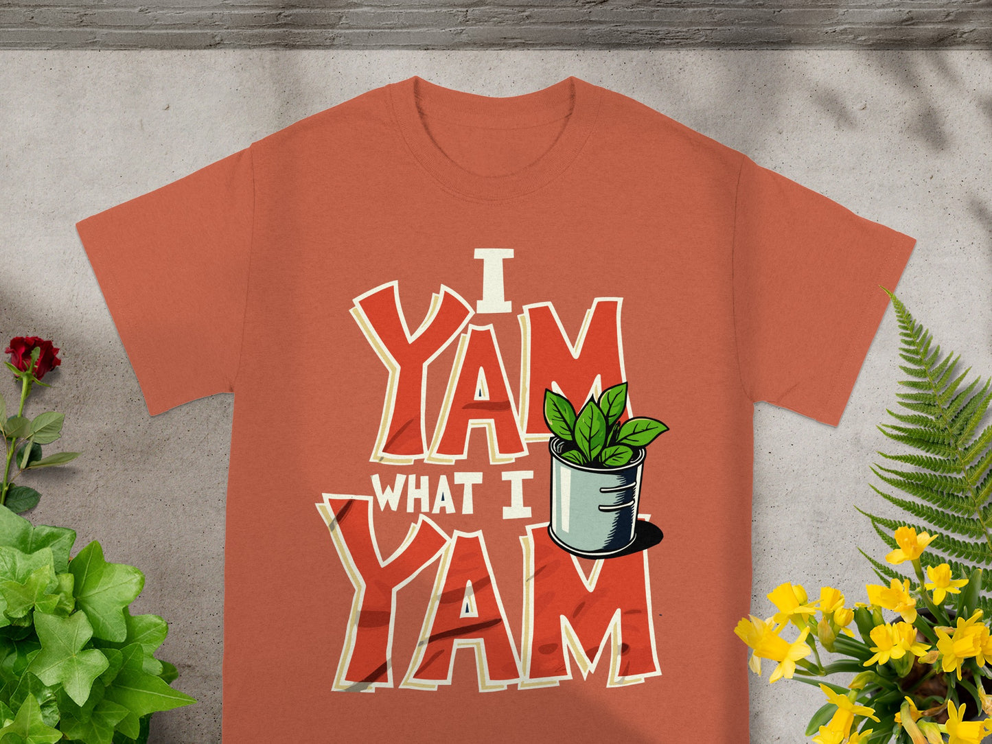 Orange t-shirt with "I Yam What I Yam" text and a potted plant.