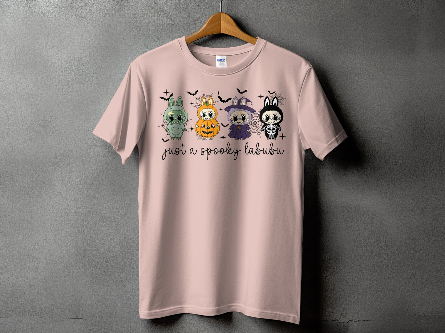 Pink t-shirt with four Halloween-themed Labubu characters and text that says "just a spooky labubu".