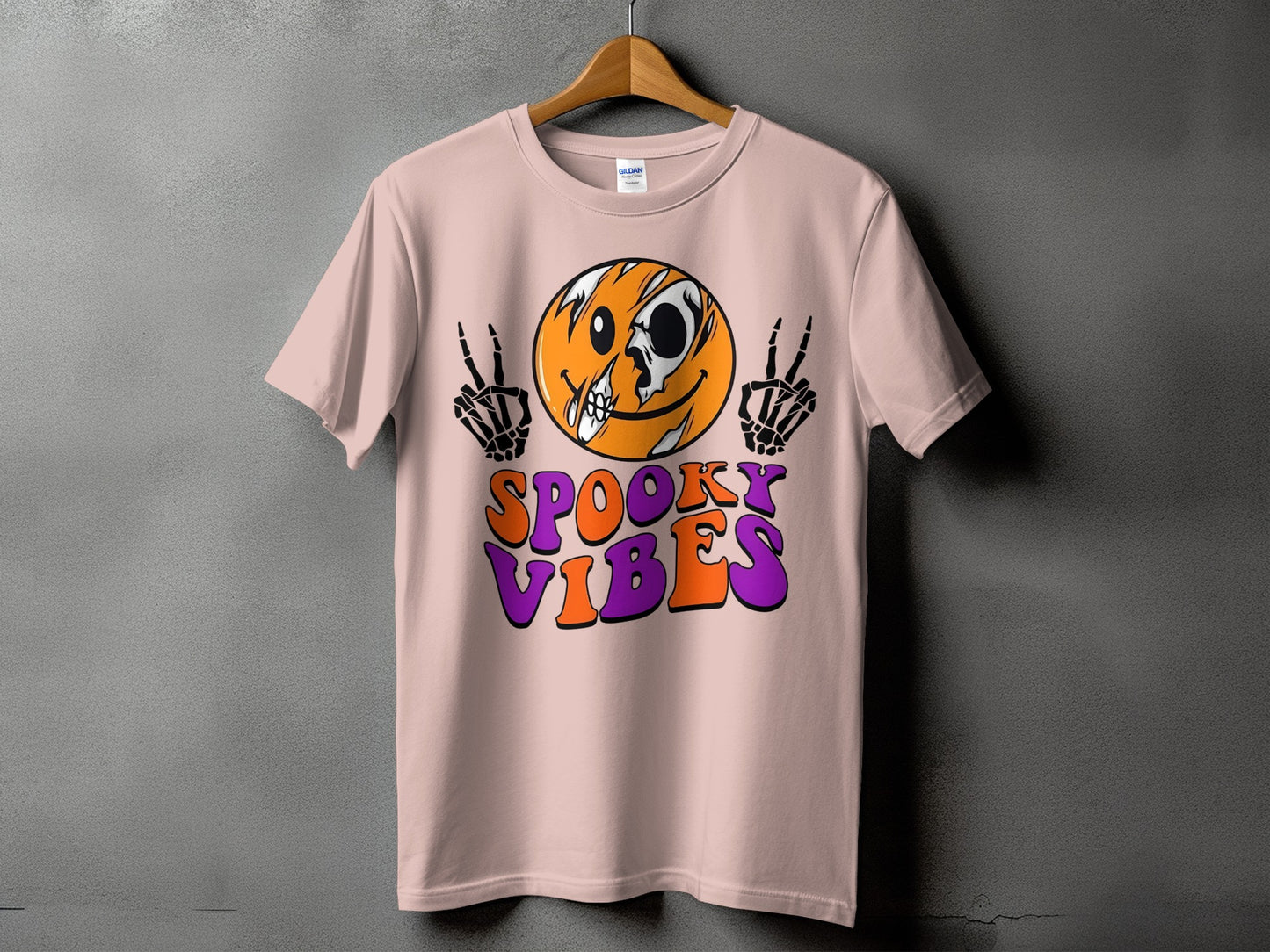 Pink t-shirt with a skull-faced smiley and skeleton hands, reading "Spooky Vibes".