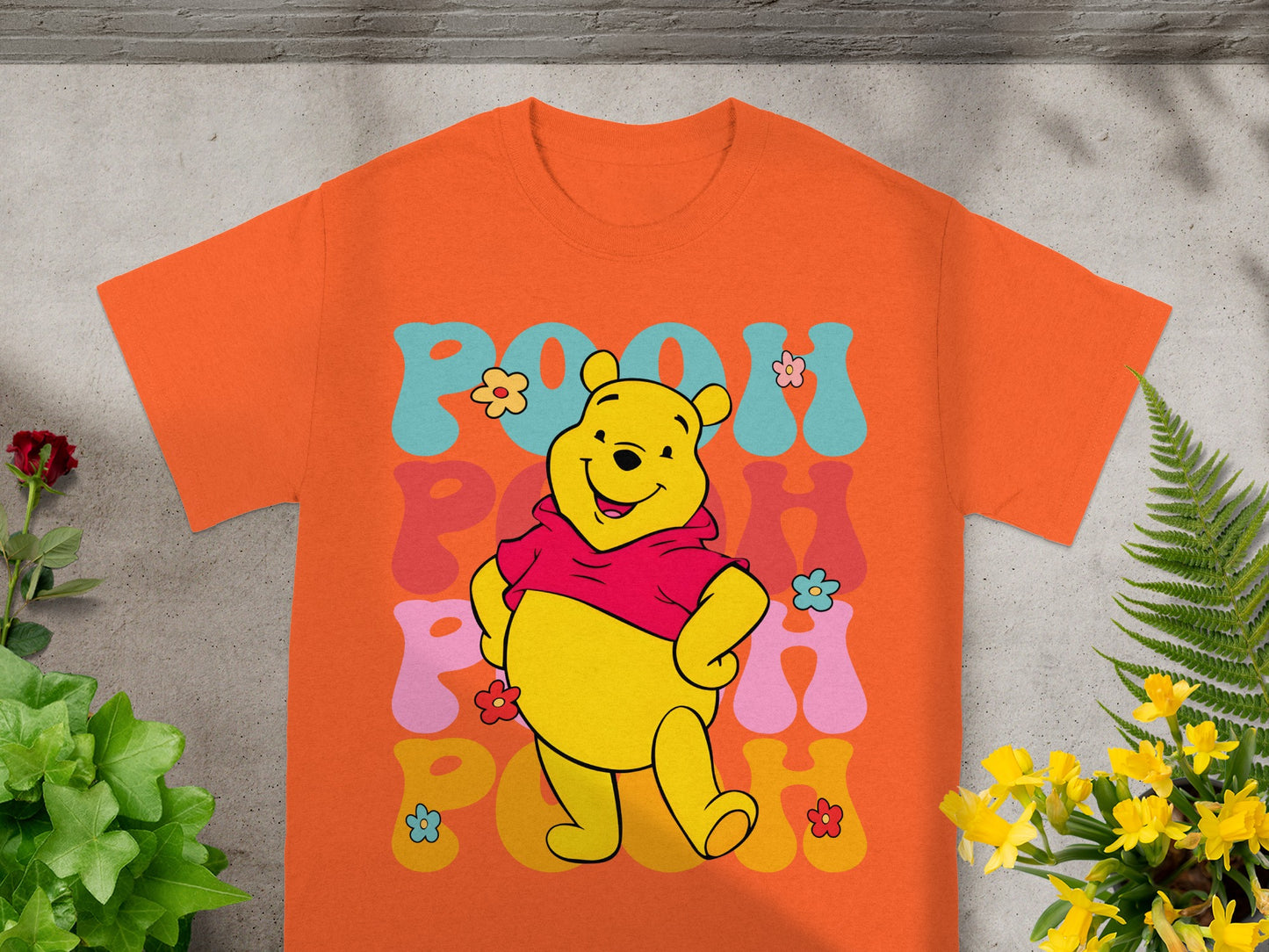 Winnie the Pooh wearing a red sweater, smiling with colorful text.