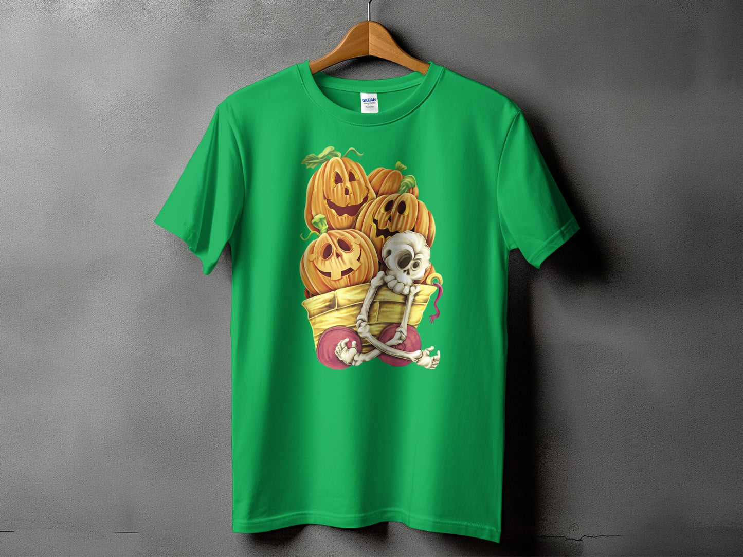 Green t-shirt with Halloween pumpkins and skeleton in a wagon graphic.