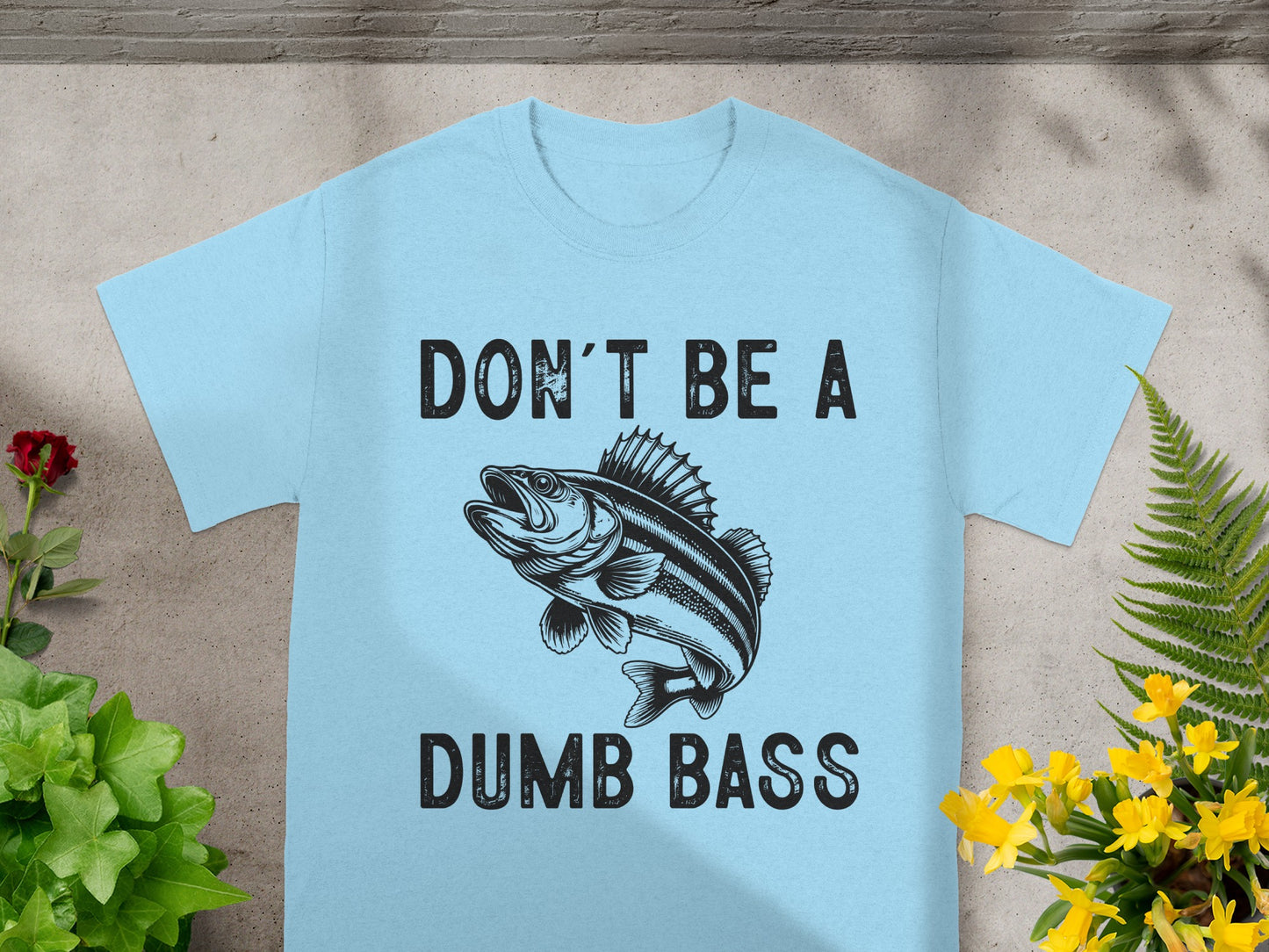 Light blue t-shirt with black text "DON'T BE A DUMB BASS" and fish illustration.