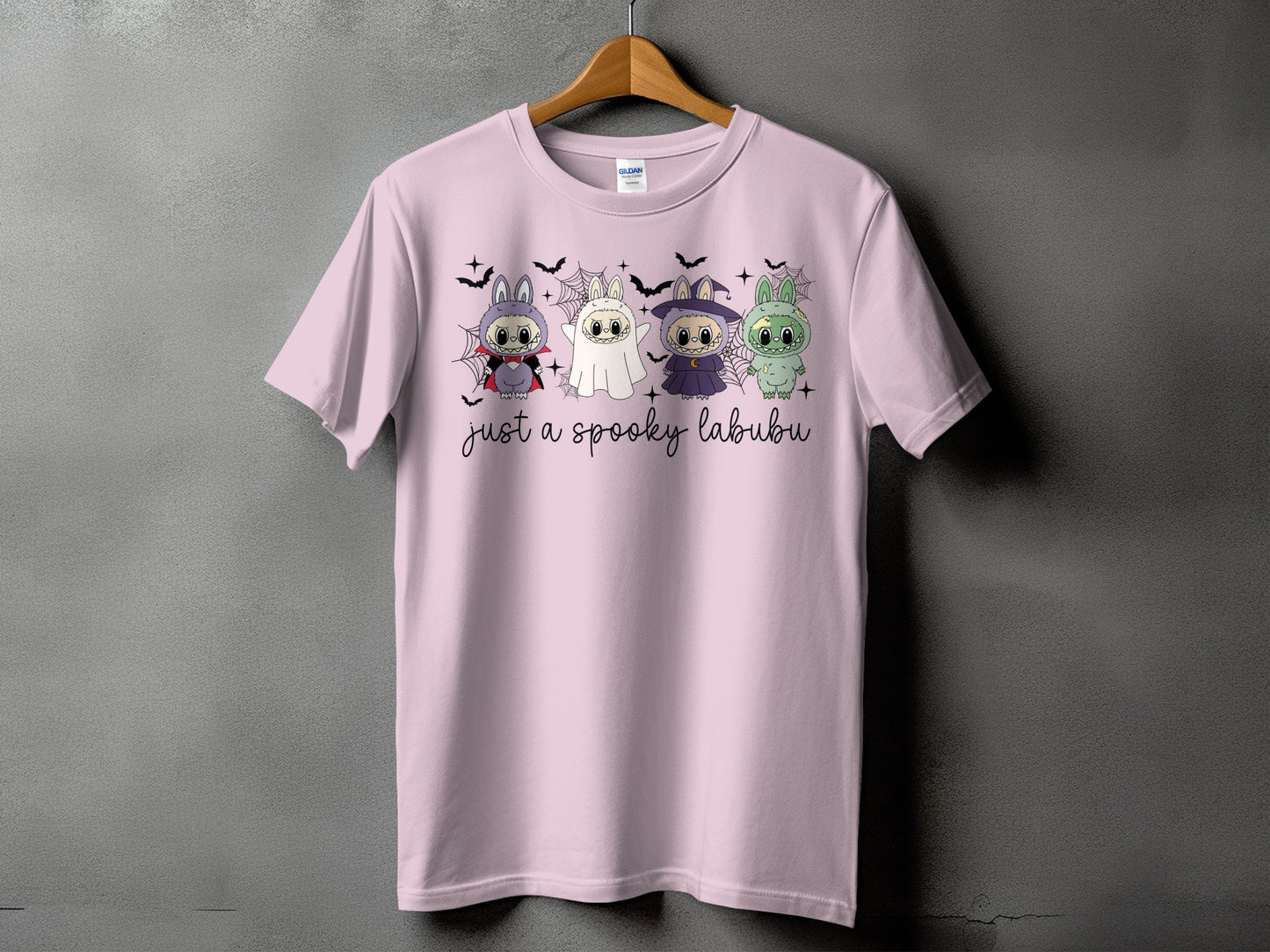 Four Halloween-themed Labubu characters on a pink t-shirt with text "just a spooky labubu".