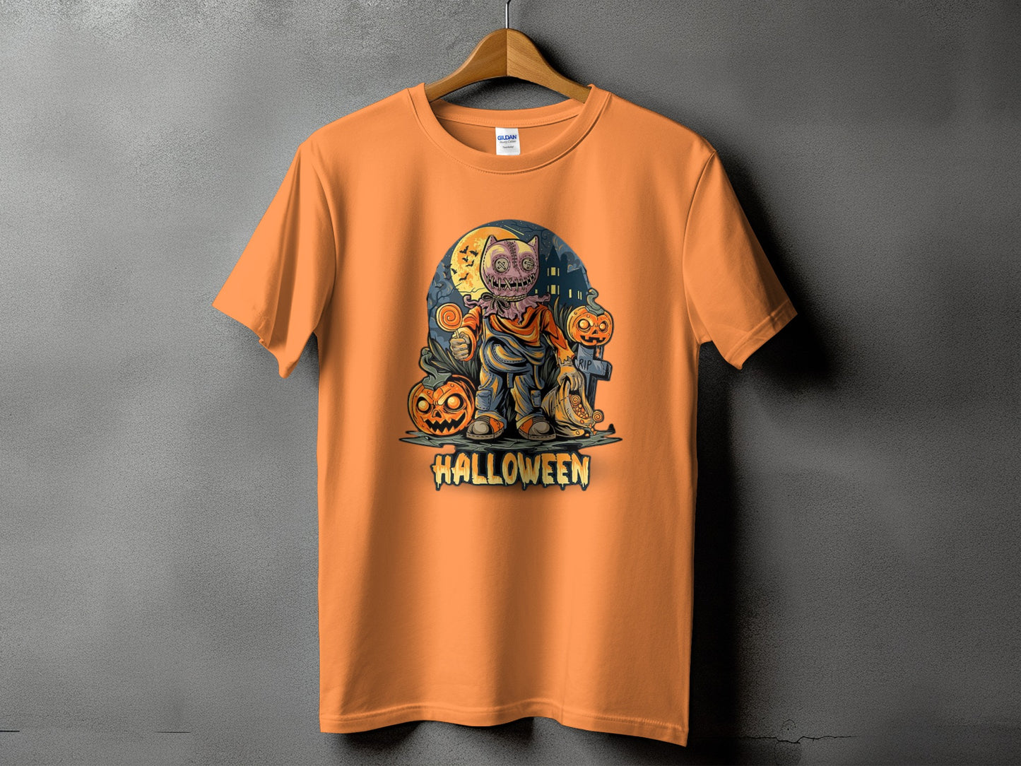 Orange t-shirt with Halloween design featuring a scarecrow, pumpkins, and a tombstone.