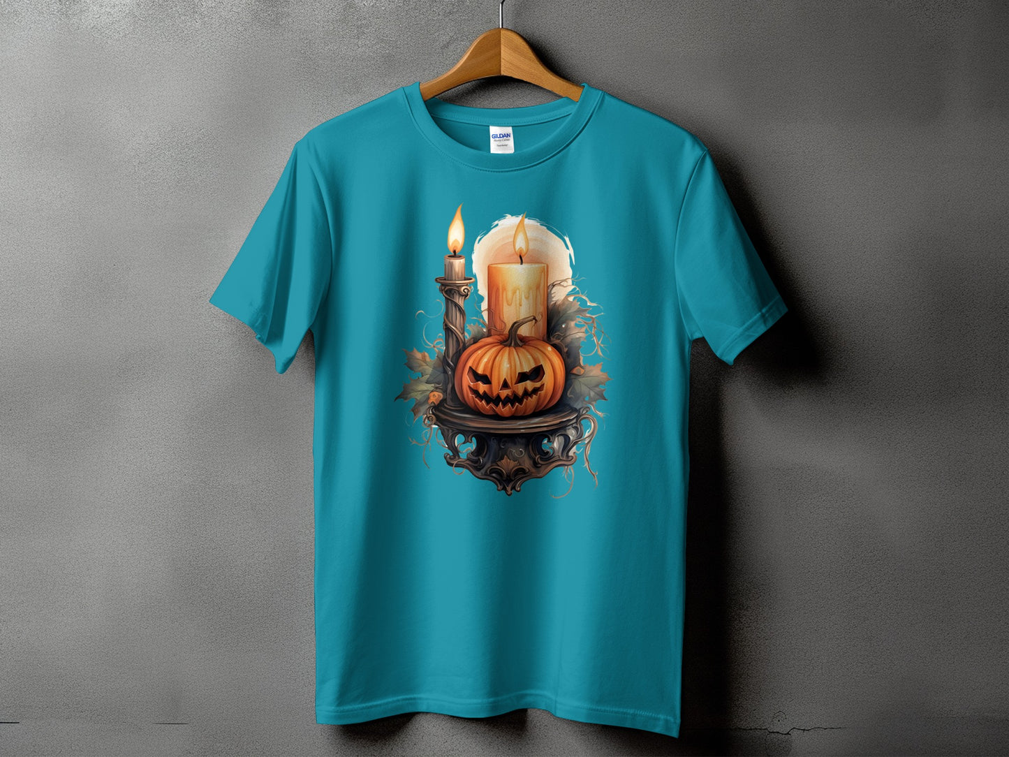 Teal t-shirt with a Halloween graphic of a jack-o'-lantern and two lit candles.