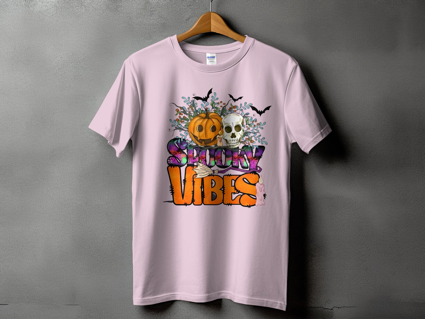 Pink t-shirt with Halloween graphic: pumpkin, skull, bats, and "Spooky Vibes" text.