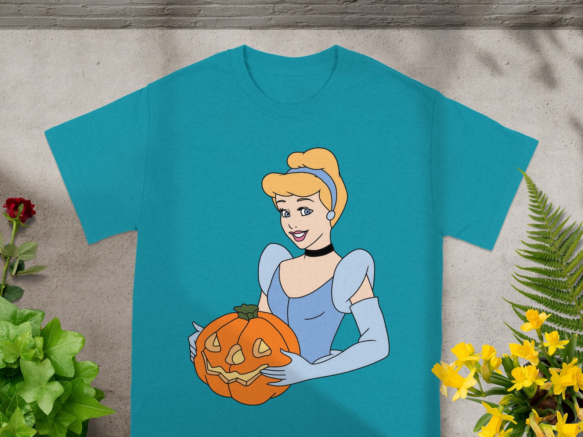 Cinderella holding a jack-o'-lantern on a teal t-shirt.