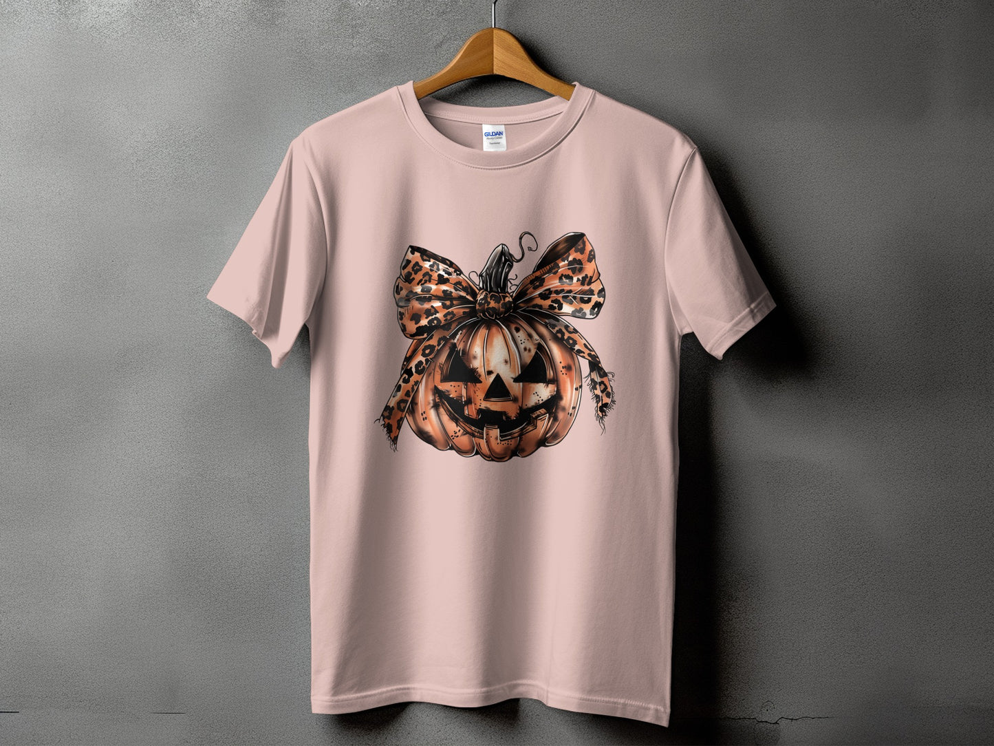 Pink t-shirt with a graphic of a jack-o'-lantern wearing a leopard print bow.