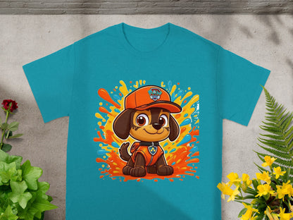 Blue t-shirt with cartoon dog wearing orange cap and vest, surrounded by colorful splashes.