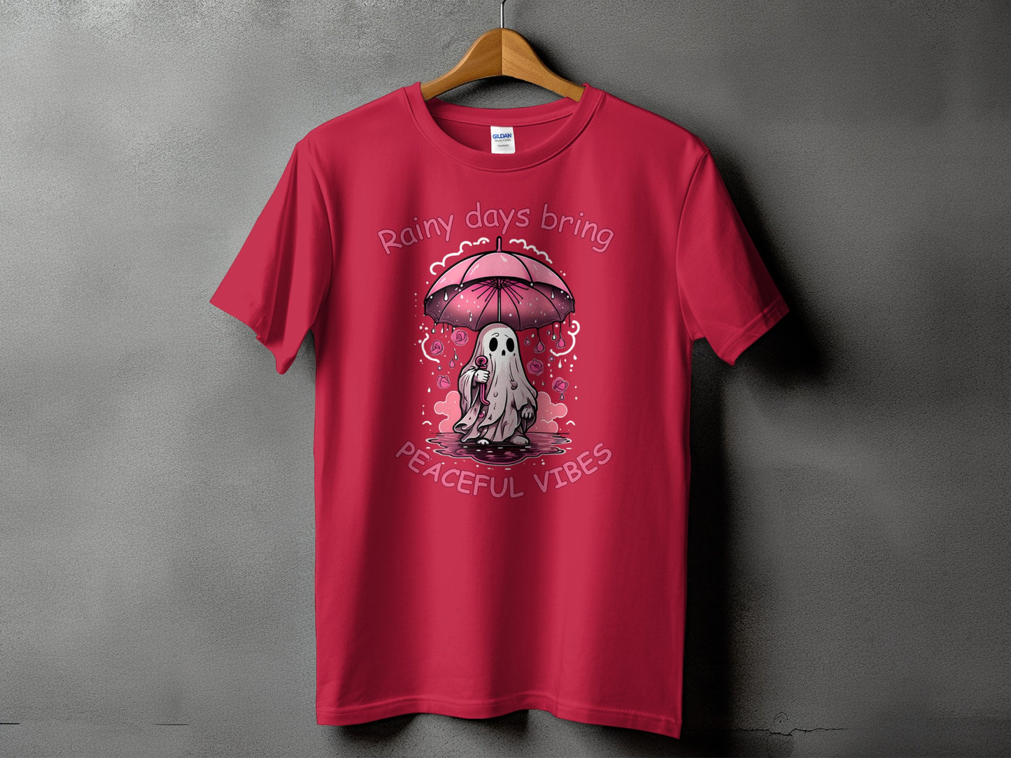 Red t-shirt with ghost under pink umbrella, text "Rainy days bring peaceful vibes".