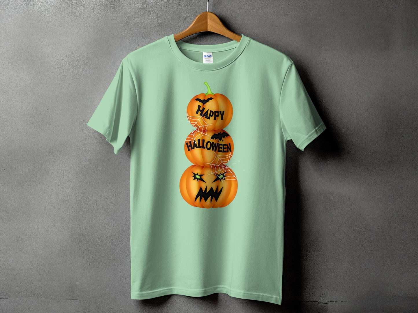 Mint green t-shirt with stacked pumpkins, bats, spiderwebs, and text reading "Happy Halloween".
