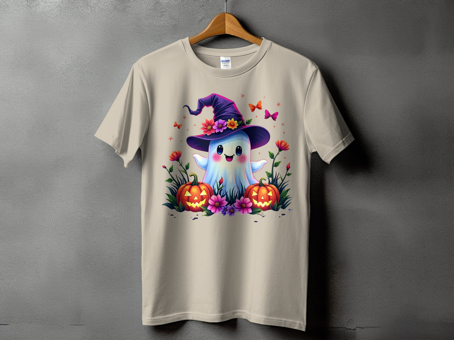 Ghost with witch hat, pumpkins, flowers, and butterflies on a tan t-shirt.