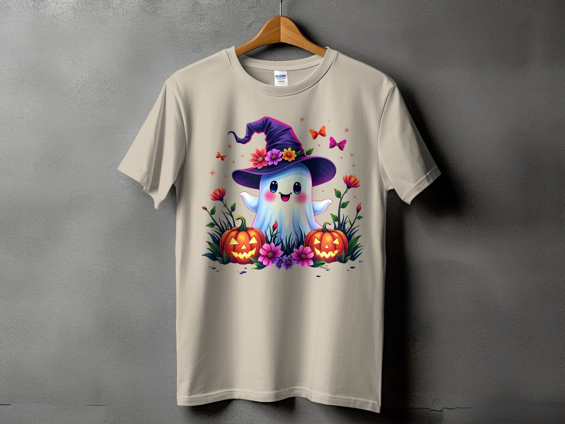 Ghost with witch hat, pumpkins, flowers, and butterflies on a tan t-shirt.